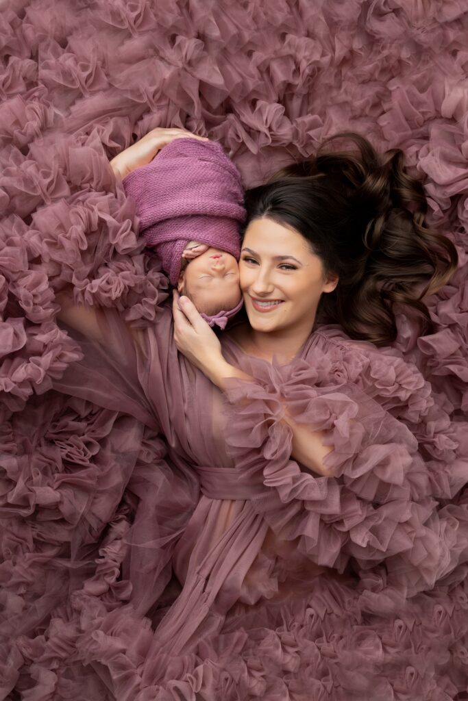 Mother holding her newborn baby wrapped in matching purple tones during a Phoenix newborn photography session. This emotional portrait highlights connection and is a signature of Phoenix newborn photography.