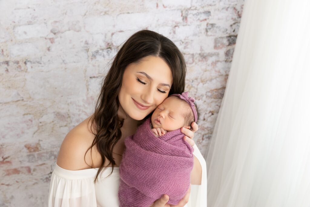 Parents holding their newborn baby during a Phoenix newborn photography session in a bright studio setting. Family portraits are an important part of Phoenix newborn photography experiences.