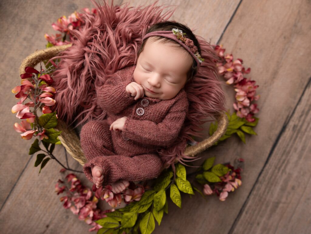 Newborn baby girl posed in floral basket setup during Phoenix newborn photography session.