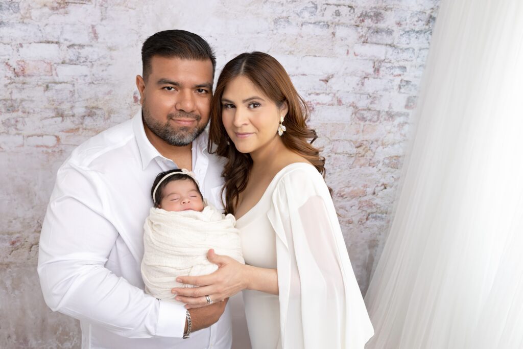 Parents holding their sleeping newborn during an in-studio session in Phoenix.