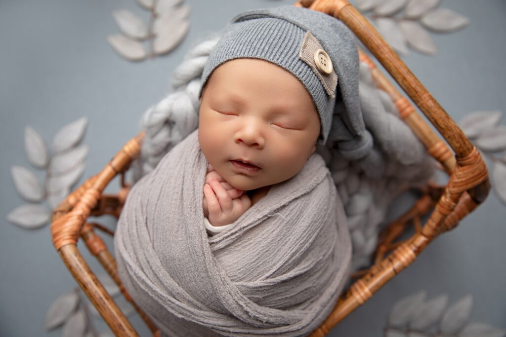 Sleeping newborn baby posed in soft gray tones for a fine-art in-studio newborn photography session.